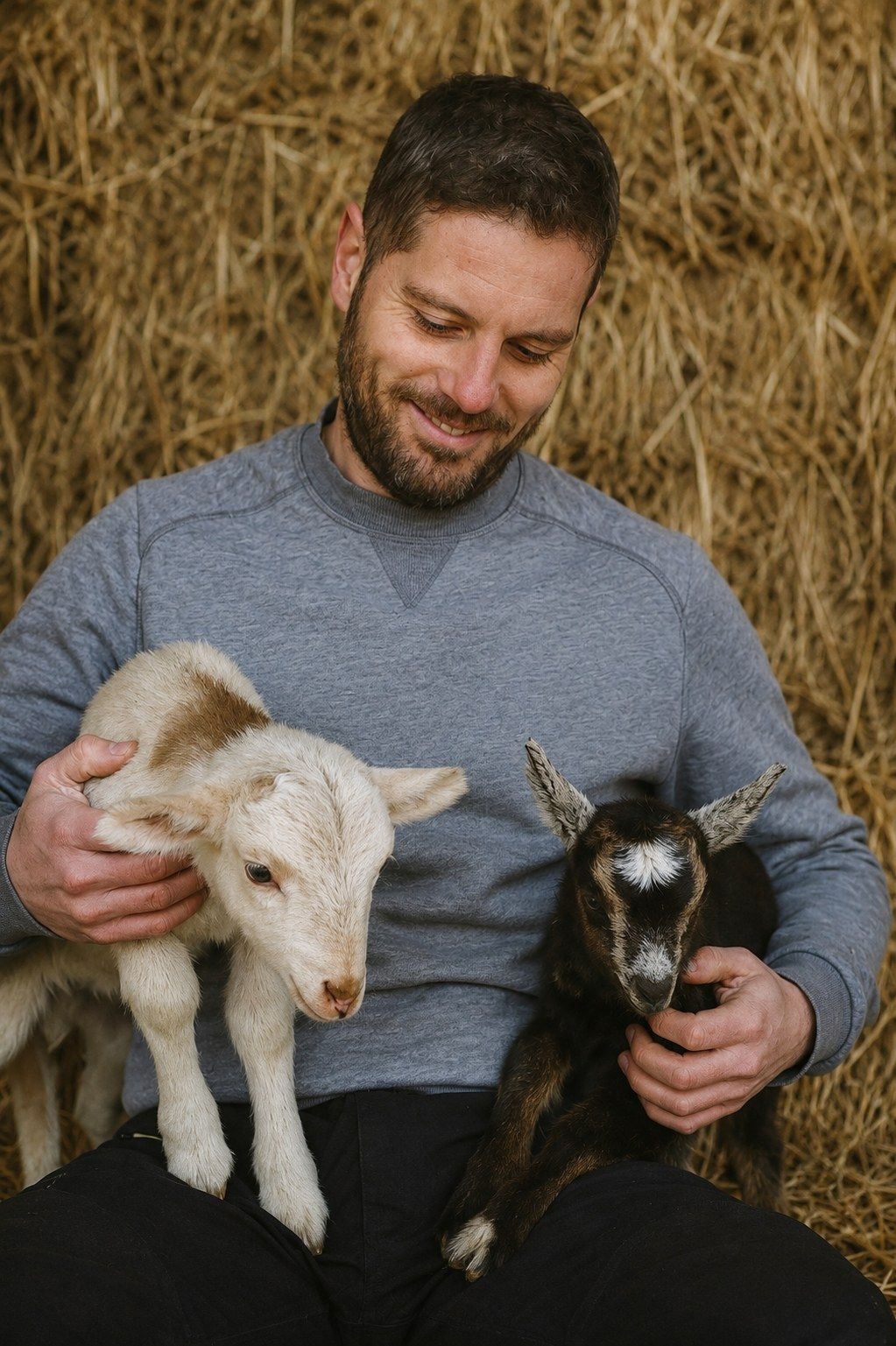 Borja Gómez sonriendo mientras sostiene dos cabritos en un entorno rural