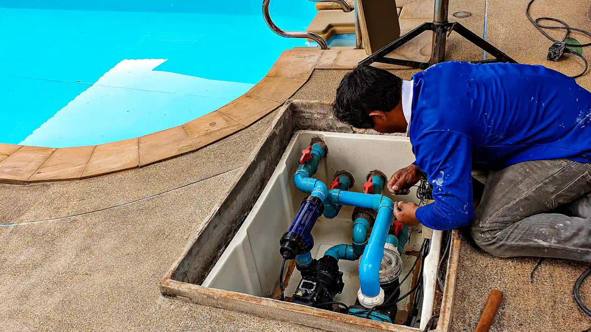 Man fixing swimming pool plumbing under concrete slab