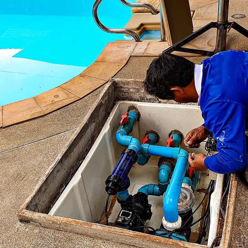 Man repairing swimming pool water pipes under concrete slab