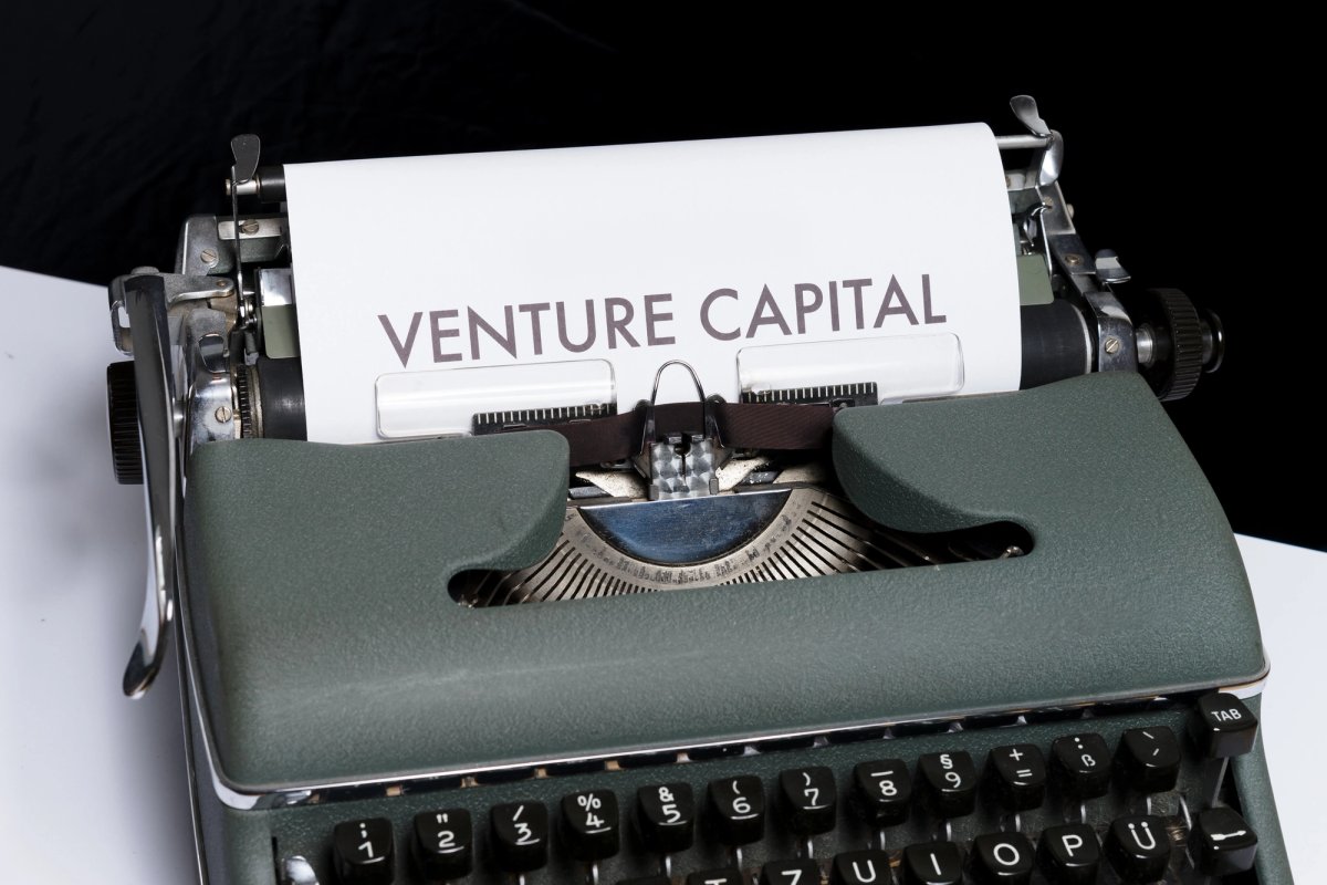 Close-up of a vintage typewriter with a sheet of paper loaded, displaying the words "VENTURE CAPITAL" in bold capital letters.