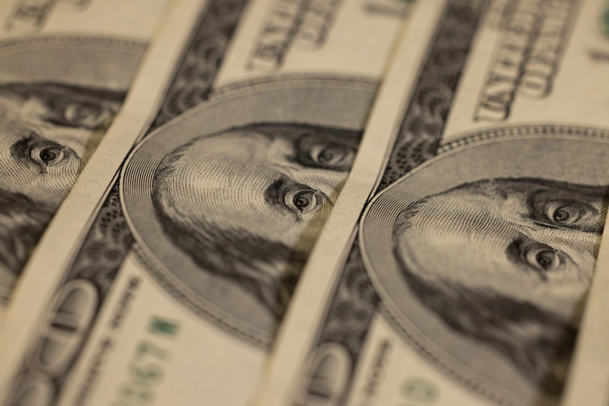 Close-up of multiple U.S. $100 bills aligned in rows, focusing on Benjamin Franklin’s portrait.
