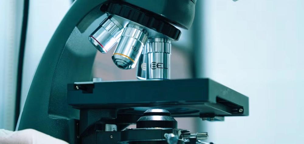 The objective lenses and stage of a laboratory microscope, close up.