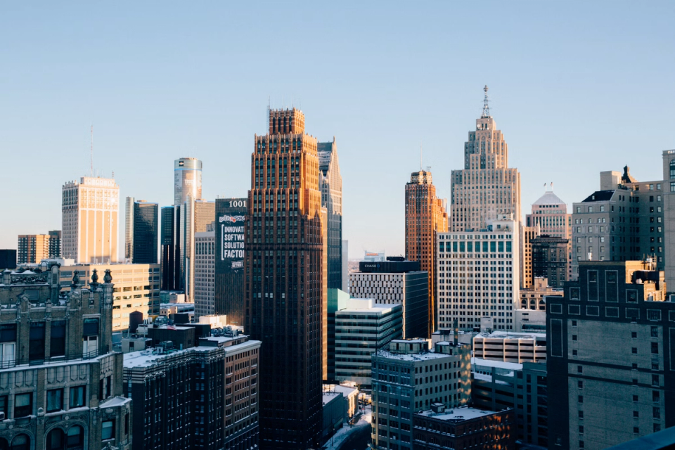 The downtown Detroit skyline in low winter sun, art deco towers against a clear sky.