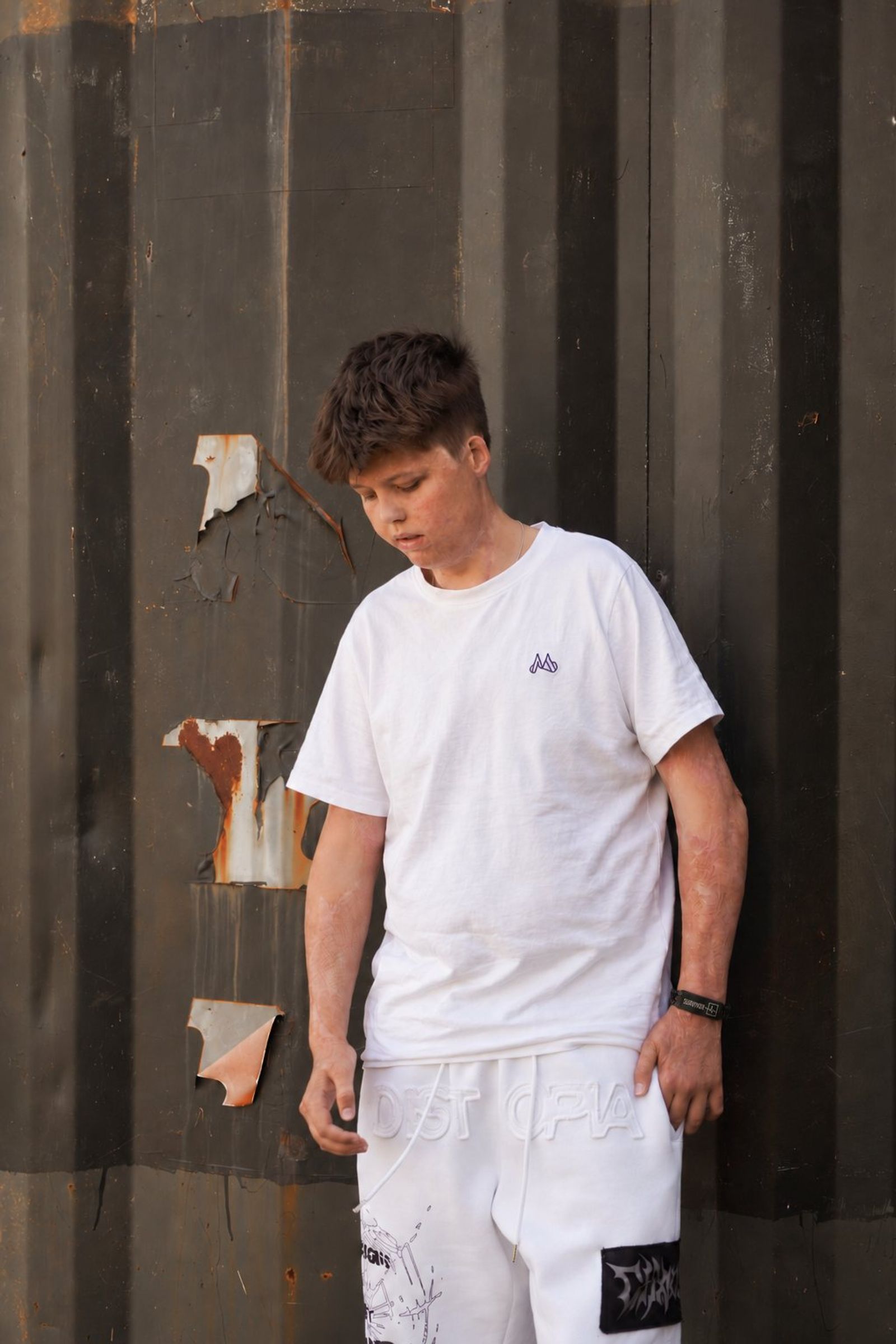 Charlie i vit t-shirt framför en mörk vägg