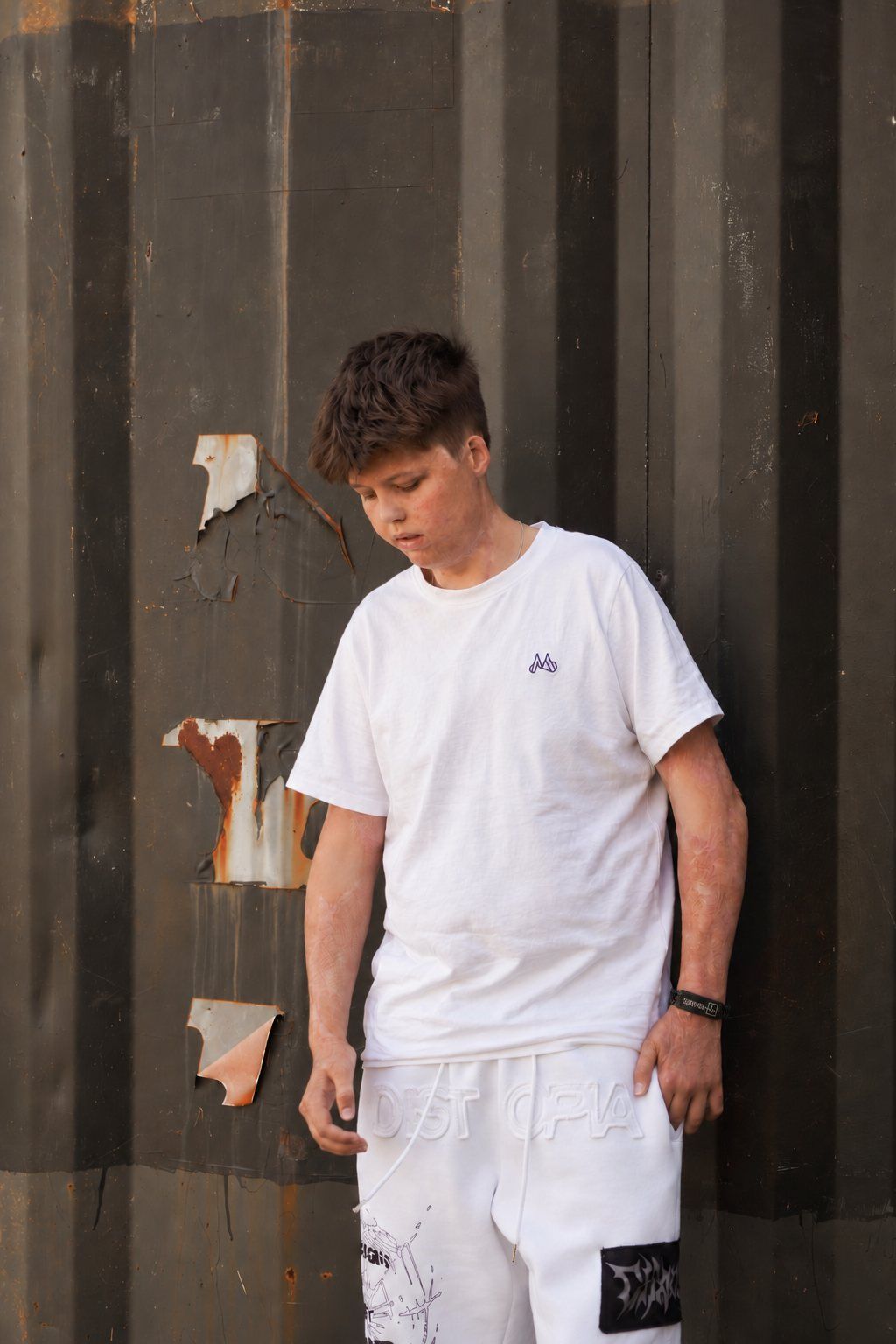 Charlie i vit t-shirt framför en mörk vägg