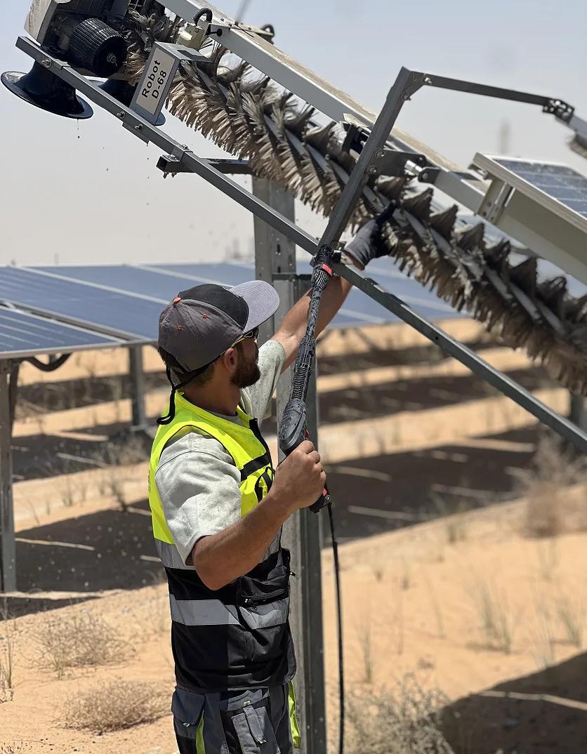 Mustakbal Clean Tech technician performing module cleaning on solar panel infrastructure at a desert solar farm