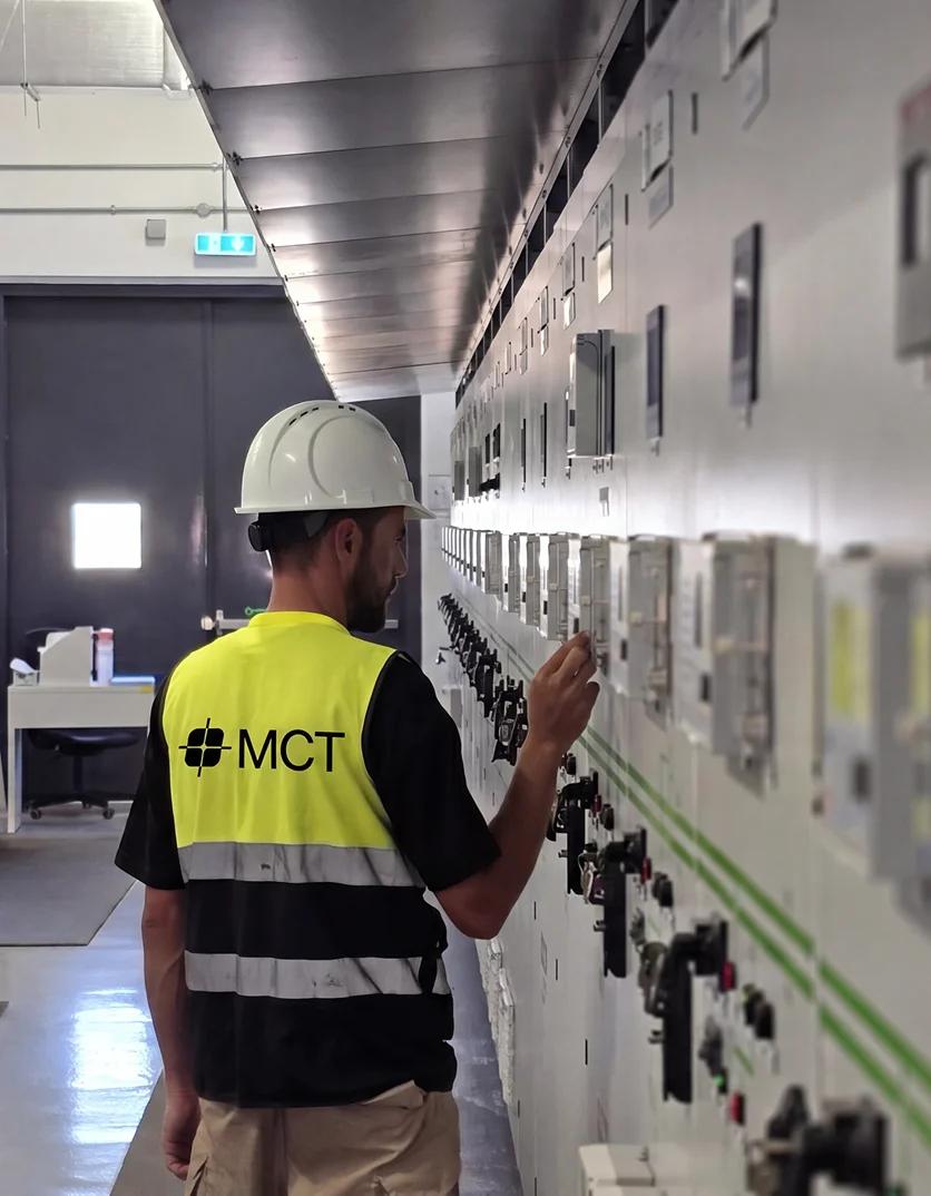 Mustakbal Clean Tech technician inspecting electrical control panels in an industrial switchgear room