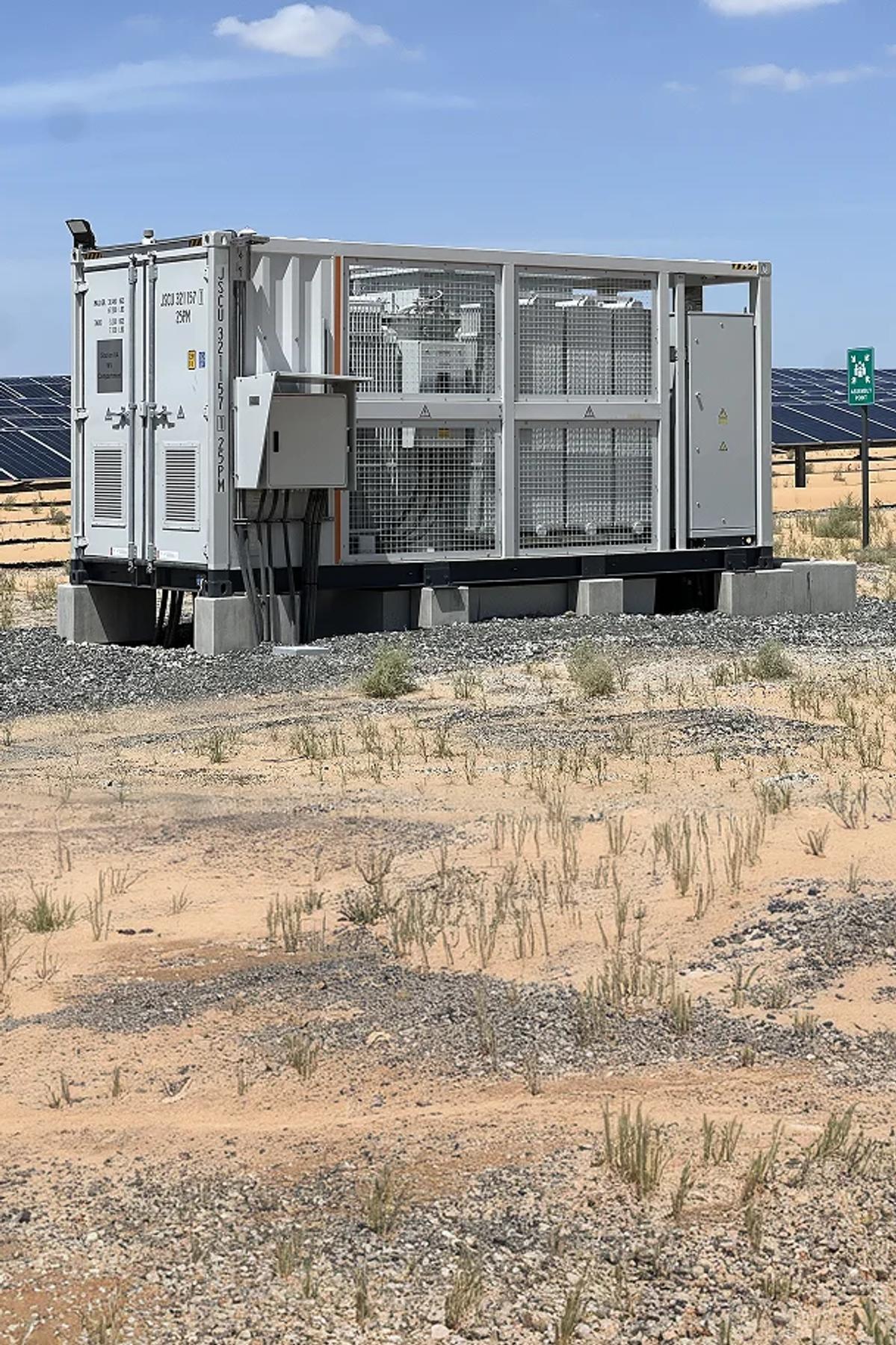 Inverter equipment at a desert solar farm with rows of solar panels