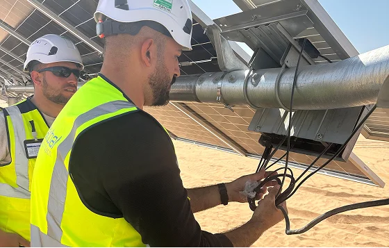 Technicians connecting electrical cabling on a solar panel array
