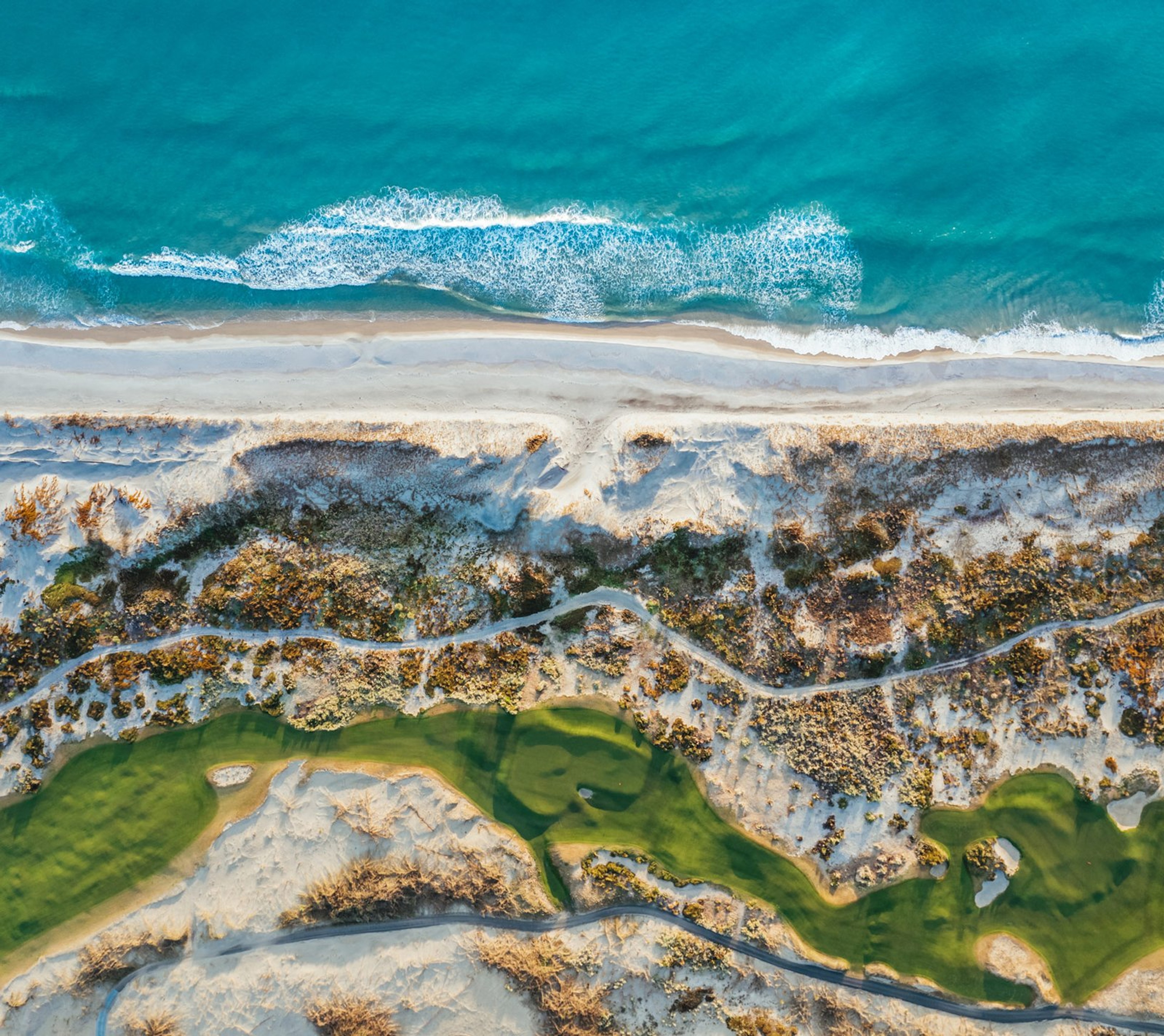Aerial view of surf, dunes and a golf course on the Mangawhai coast