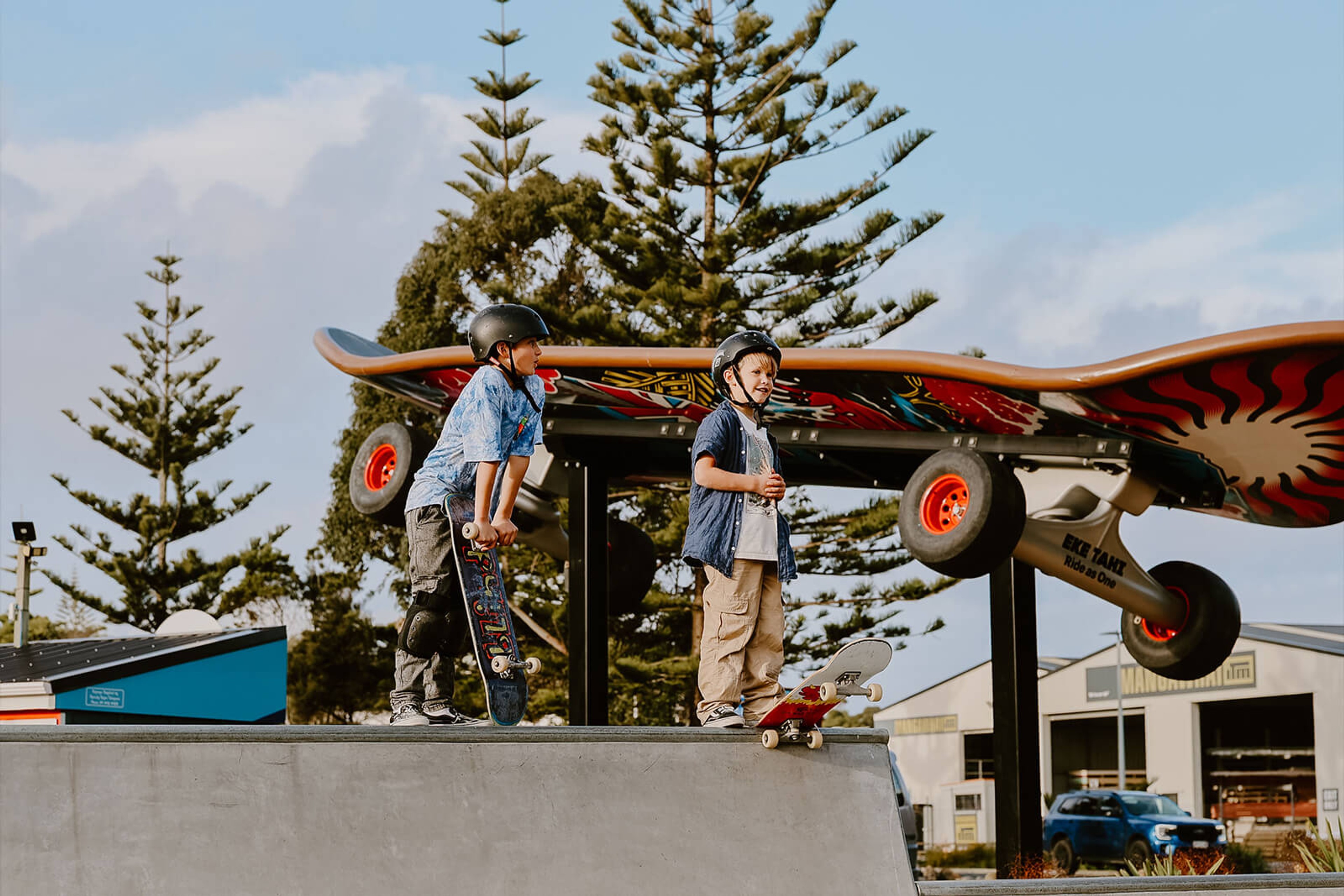 Kids skating next to a giant skateboard