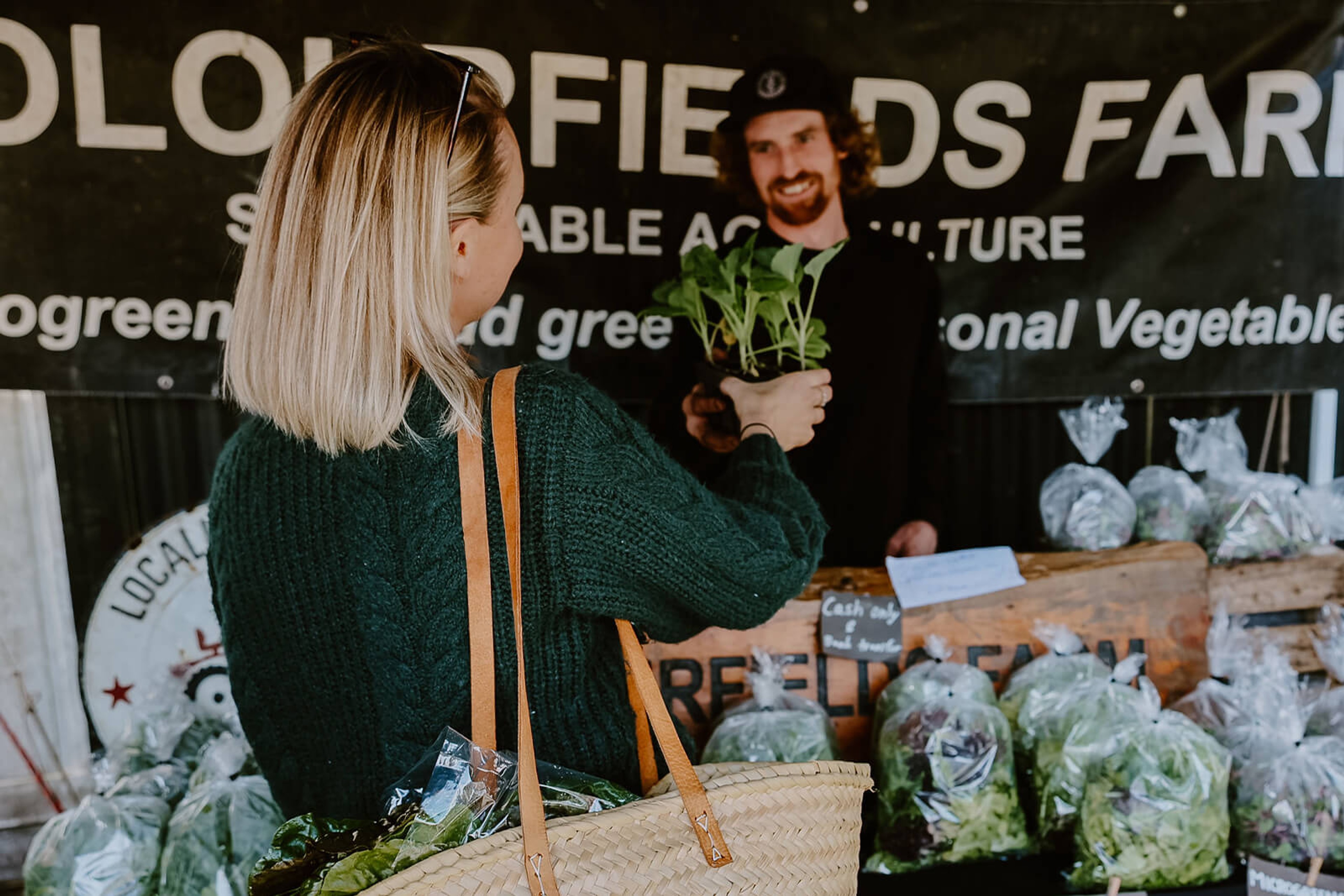 Woman buying a plant from stall at farmers market