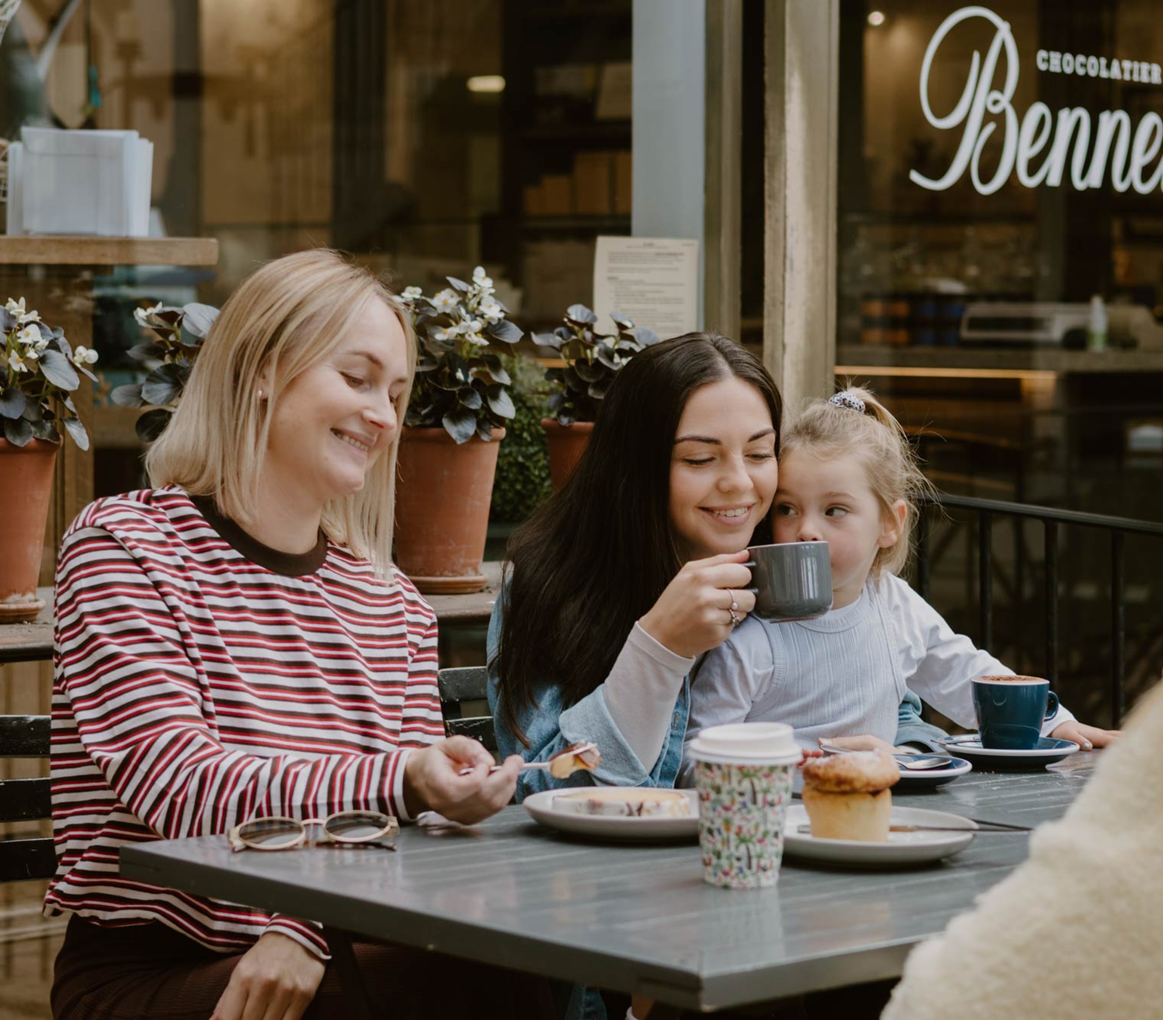 Friends and a child sharing coffee outside a café