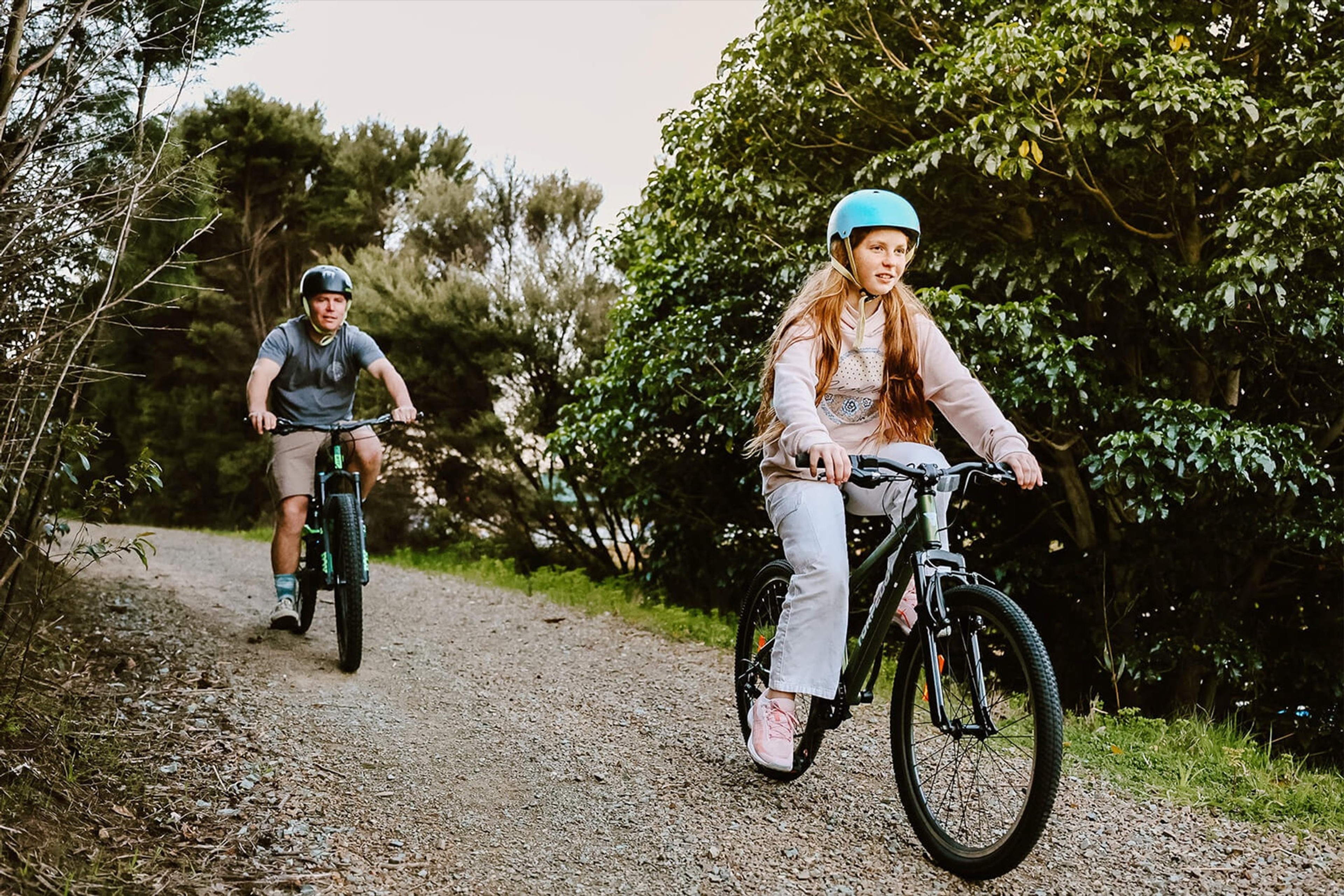Two riders on a gravel trail through native bush