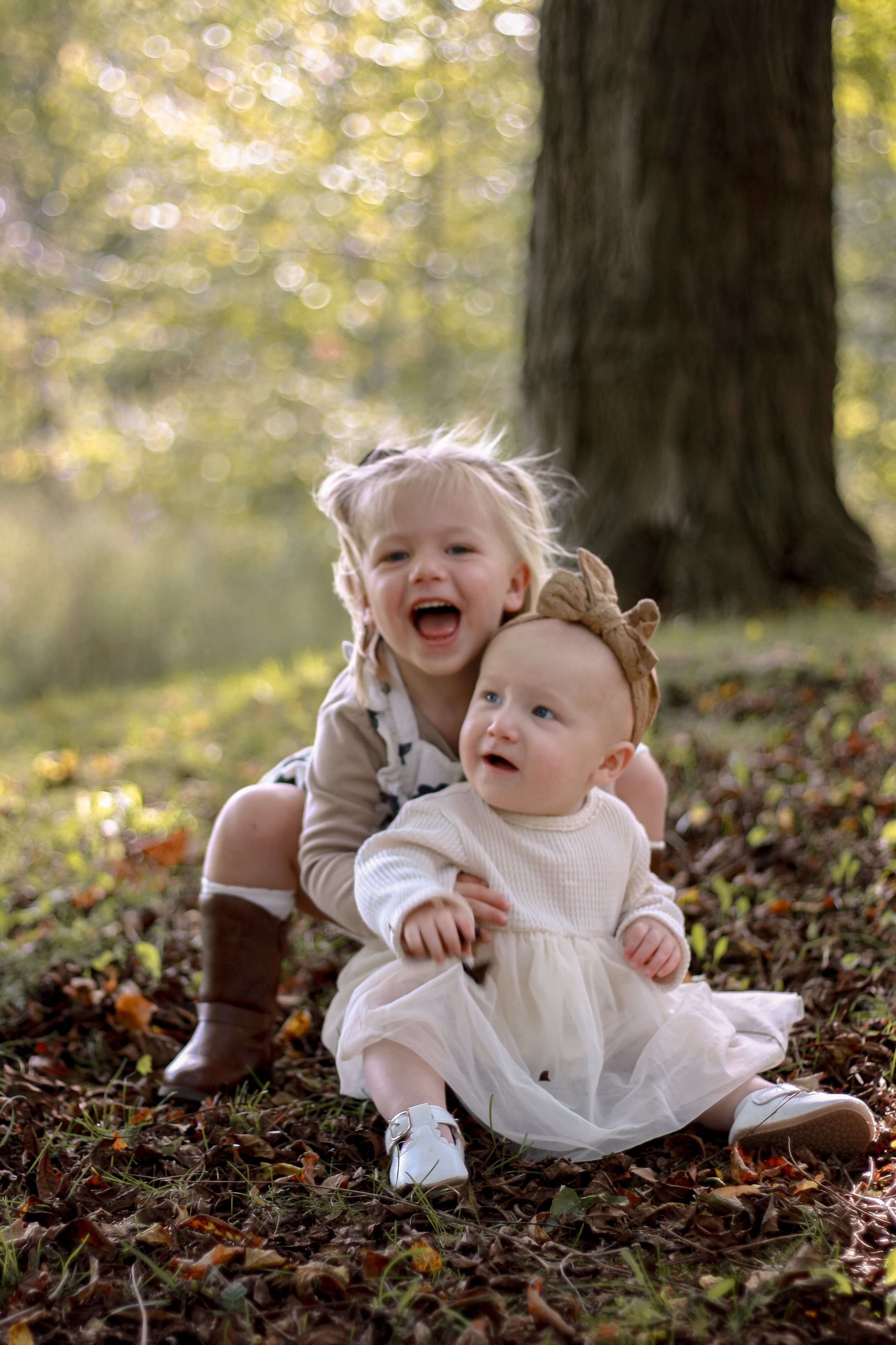 toddler hugging baby sister from behind smiling with joy - Newmarket Family Photography