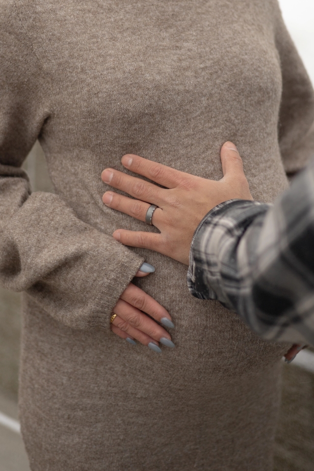 Close up of expecting dad's hand on pregnant mom's baby bump.