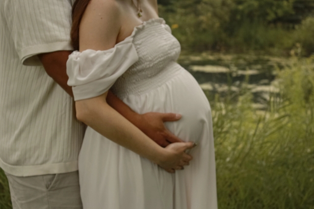 close up of baby bump, dad is standing behind mom hugging her holding baby bump - Maternity Photography