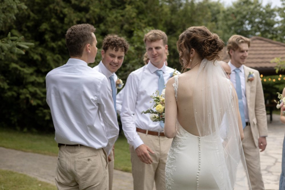 documentary moment of bride interacting with groomsmen after summer wedding ceremony