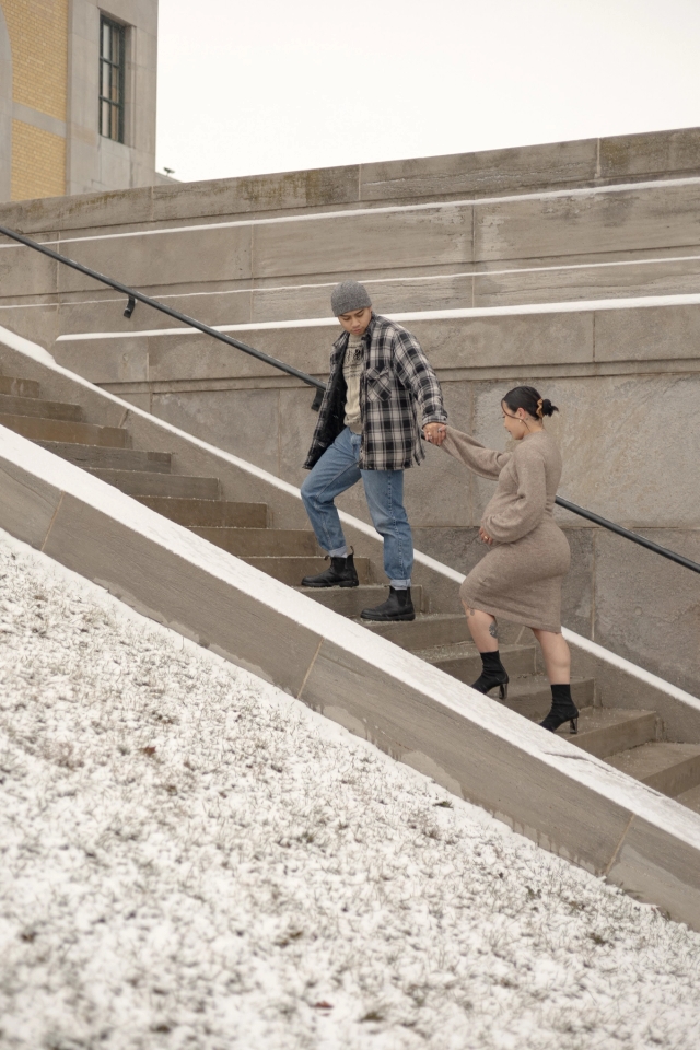 Natural moment maternity photo of an expectant mother walking up stairs near the iconic lakeside view at the R.C. Harris Water Treatment Plant while husband leads the way holding her hand.