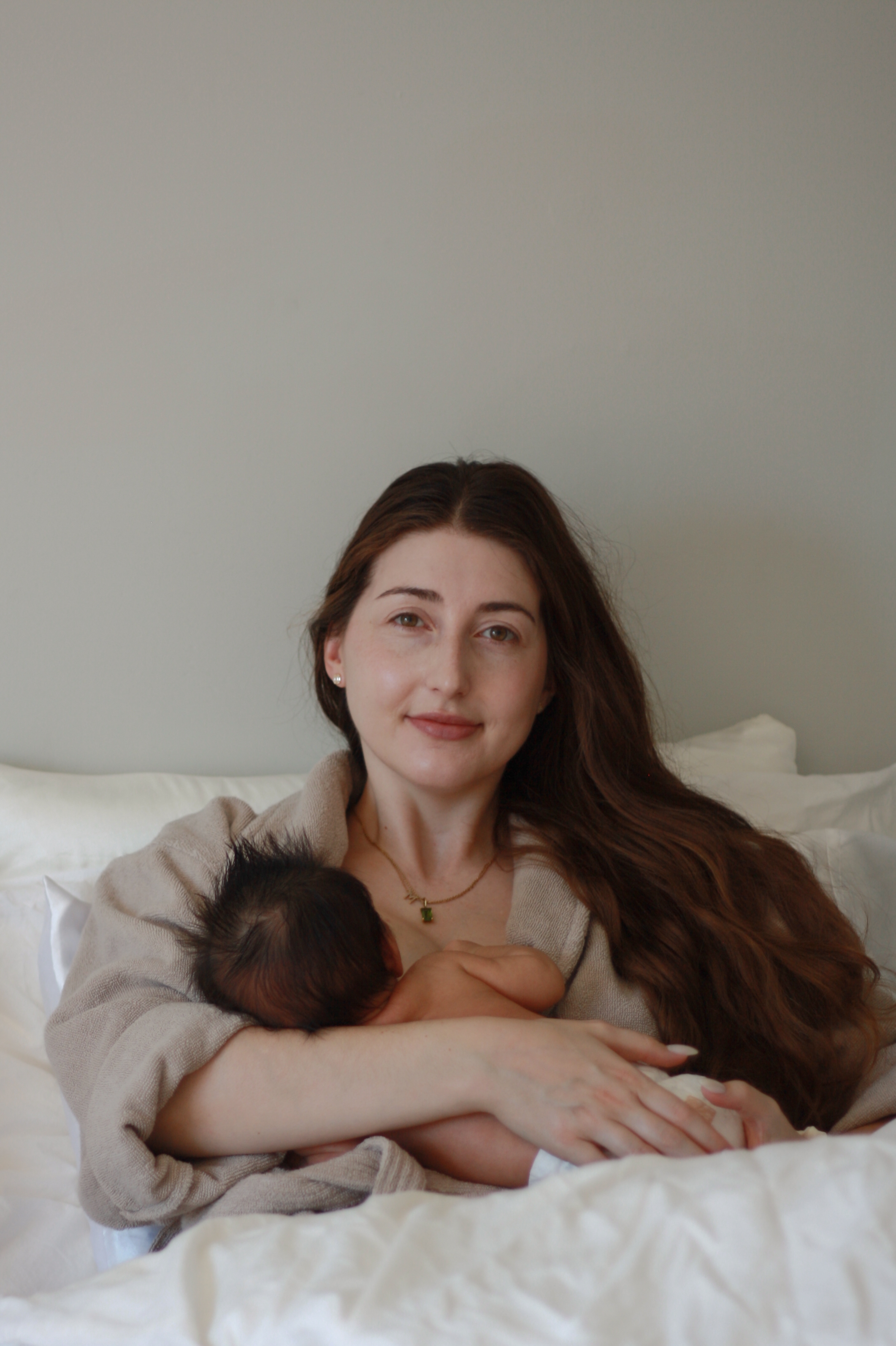 mom with long brown hair holding newborn baby breastfeeding - Newborn Photography