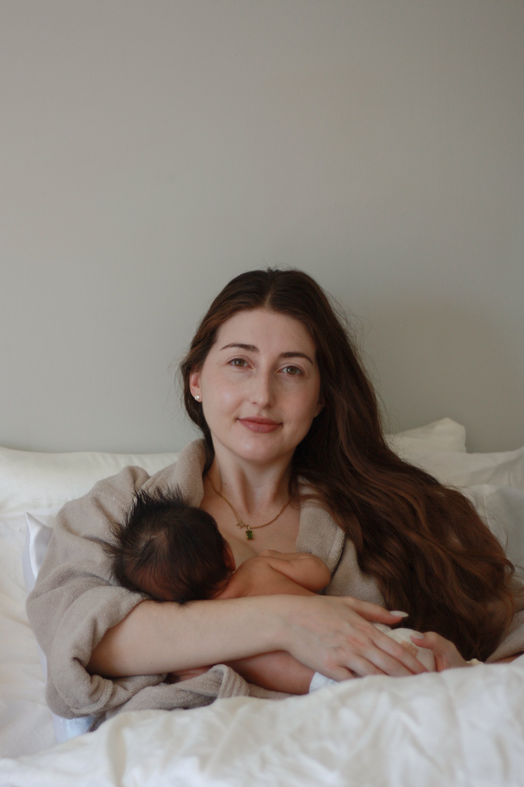 mom with long brown hair holding newborn baby breastfeeding - Newmarket Newborn Photography