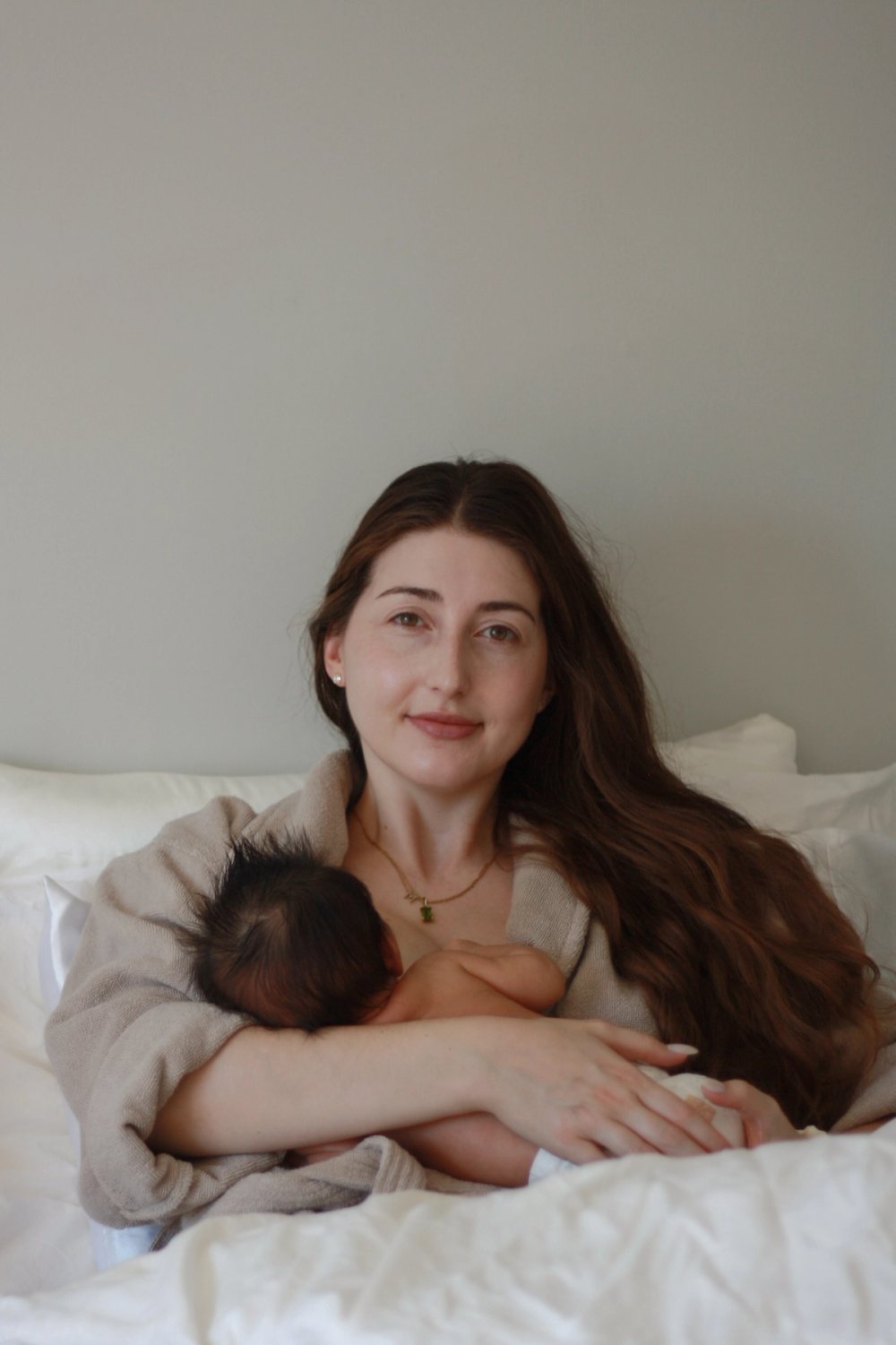 mom with long brown hair holding newborn baby breastfeeding - Newmarket Newborn Photography