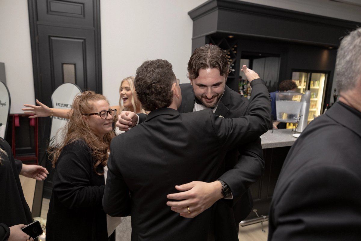 Groom hugging guest during wedding cocktail hour