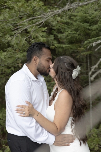 bride and groom kissing with evergreen trees in background - Tobermory Elopement Photography
