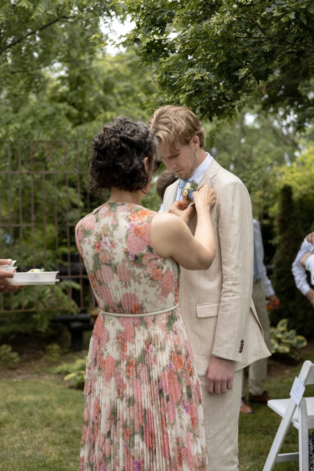 mother of groom pinning boutonniere before wedding ceremony