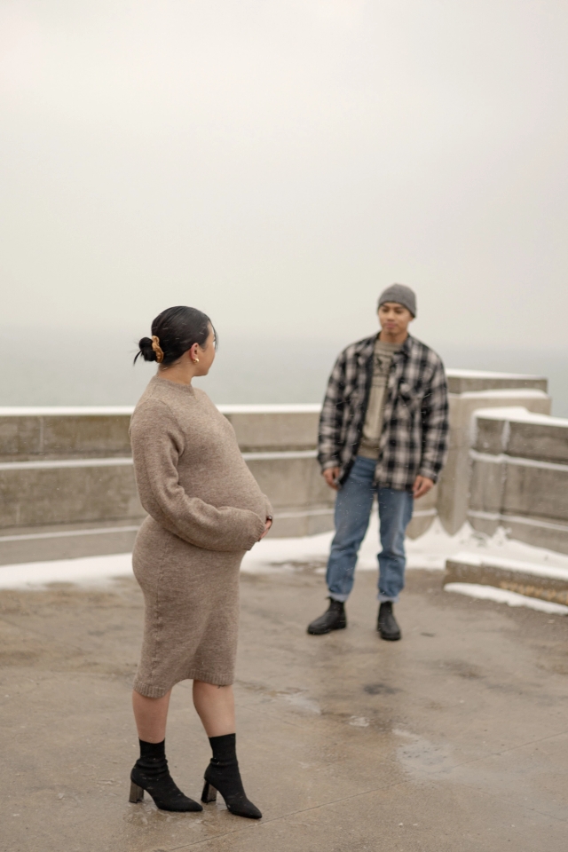 Elegant winter maternity photoshoot at a lakeside rooftop in Scarborough, Ontario with Art Deco Architecture