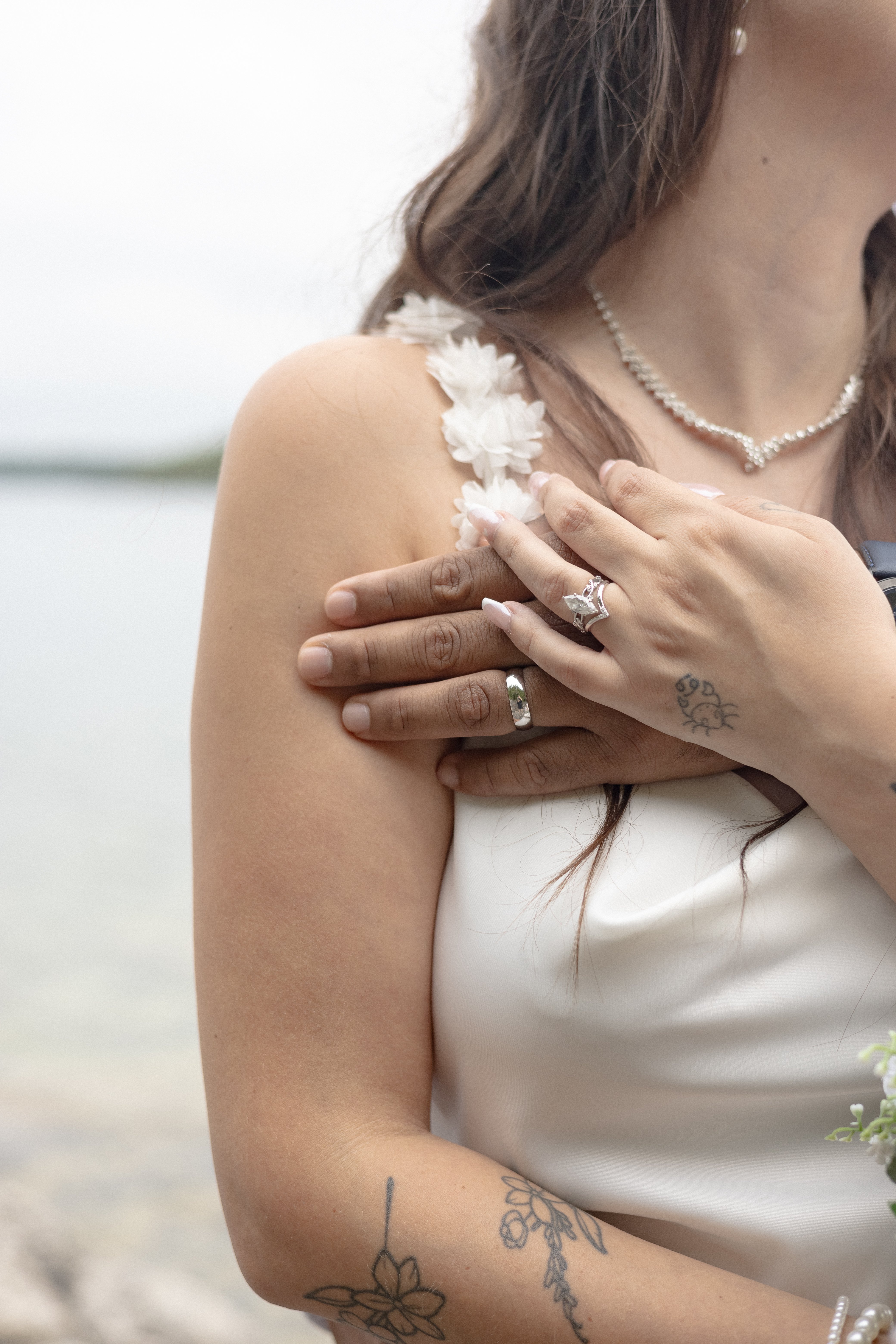 a woman's shoulder with a man's hand resting on her right chest showcasing a wedding band - Tobermory Elopement Photography