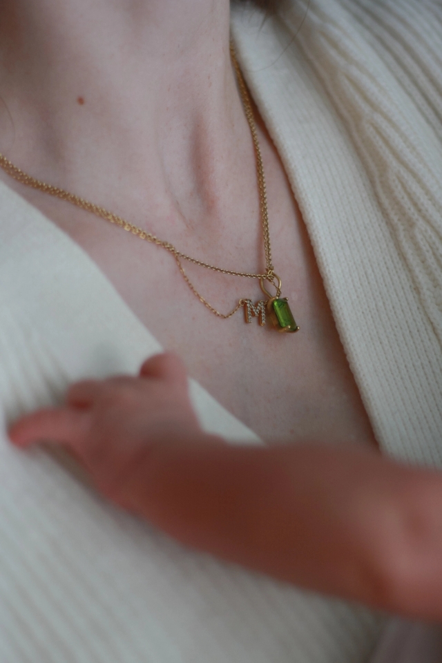 close up of baby's hand and mom's necklace with the letter 'M' and August birth stone - Newborn Photography