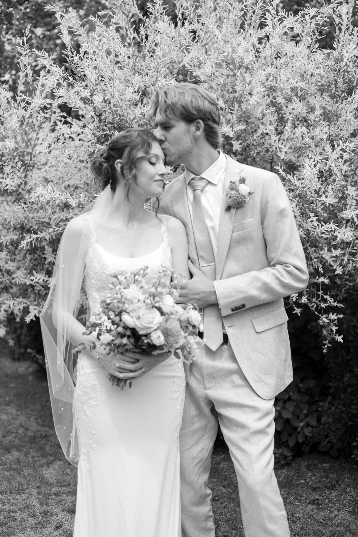 husband kissing wife on forehead in portrait