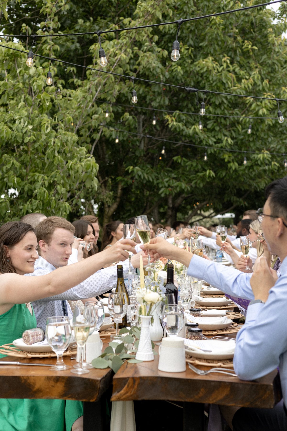 Guests raising champagne glass during outdoor evening wedding reception