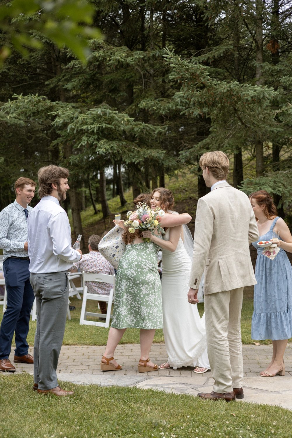 Bride hugging wedding guest holding bouquets
