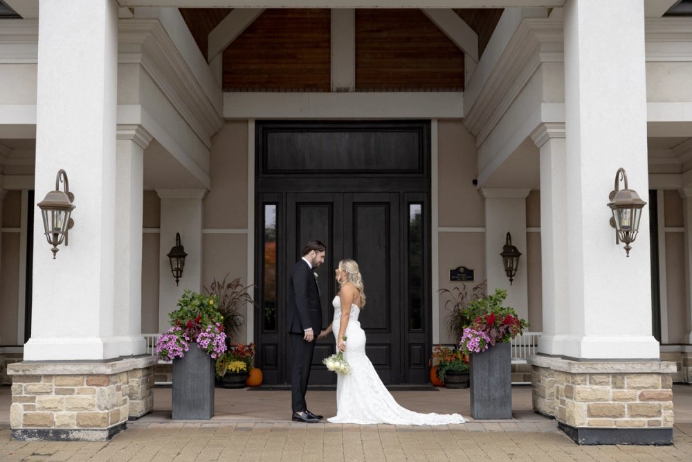 bride and groom holding hands in front of entrance to Barrie Country Club