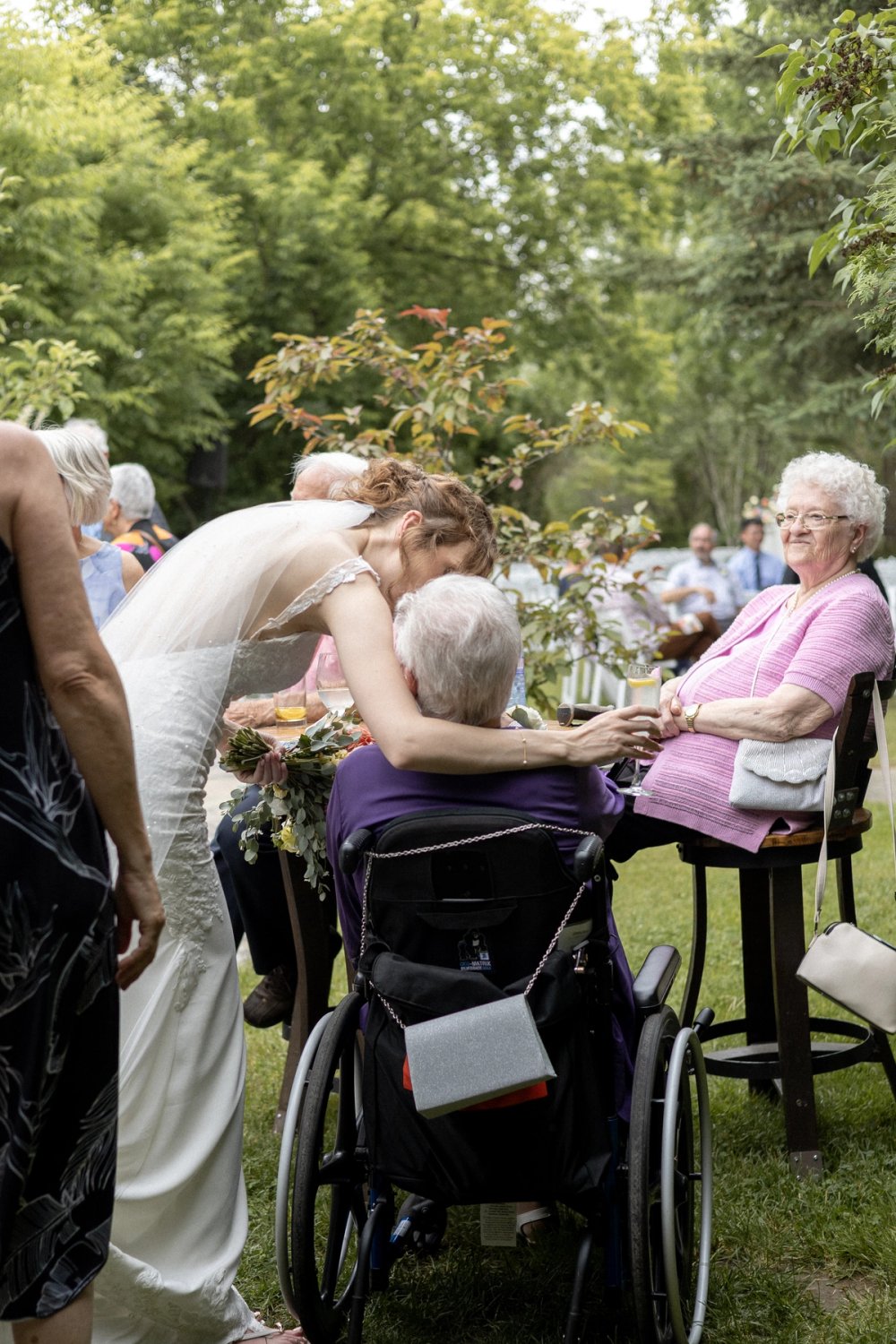 bride hugging elderly family member in wheelchair during cocktail reception
