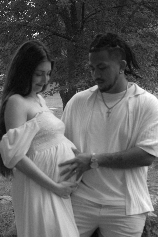 mom and dad holding baby bump while looking at it, black & white - Maternity photography