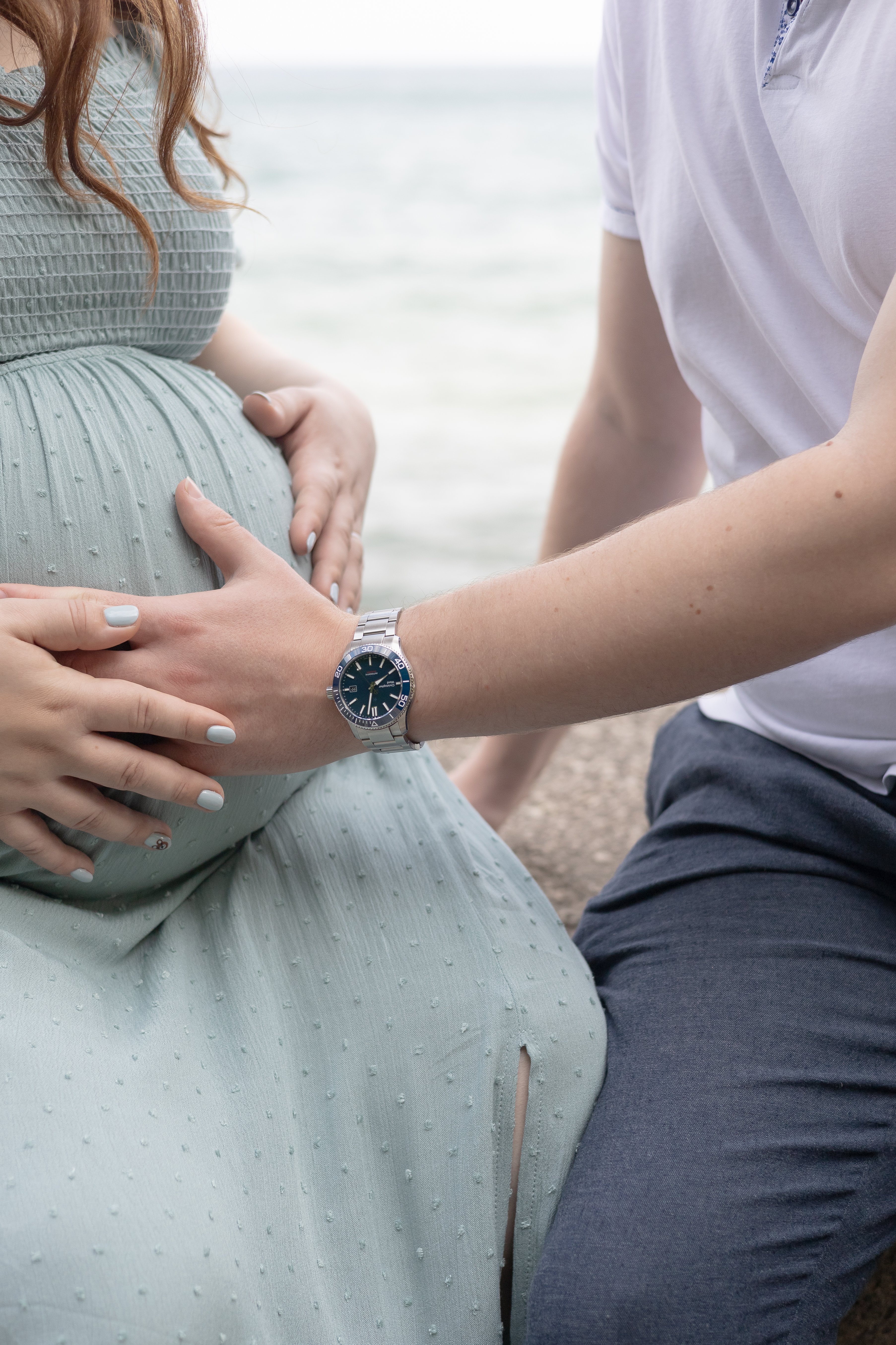 Close up of mom and dad touching baby bump during maternity photos at an Ontario beach