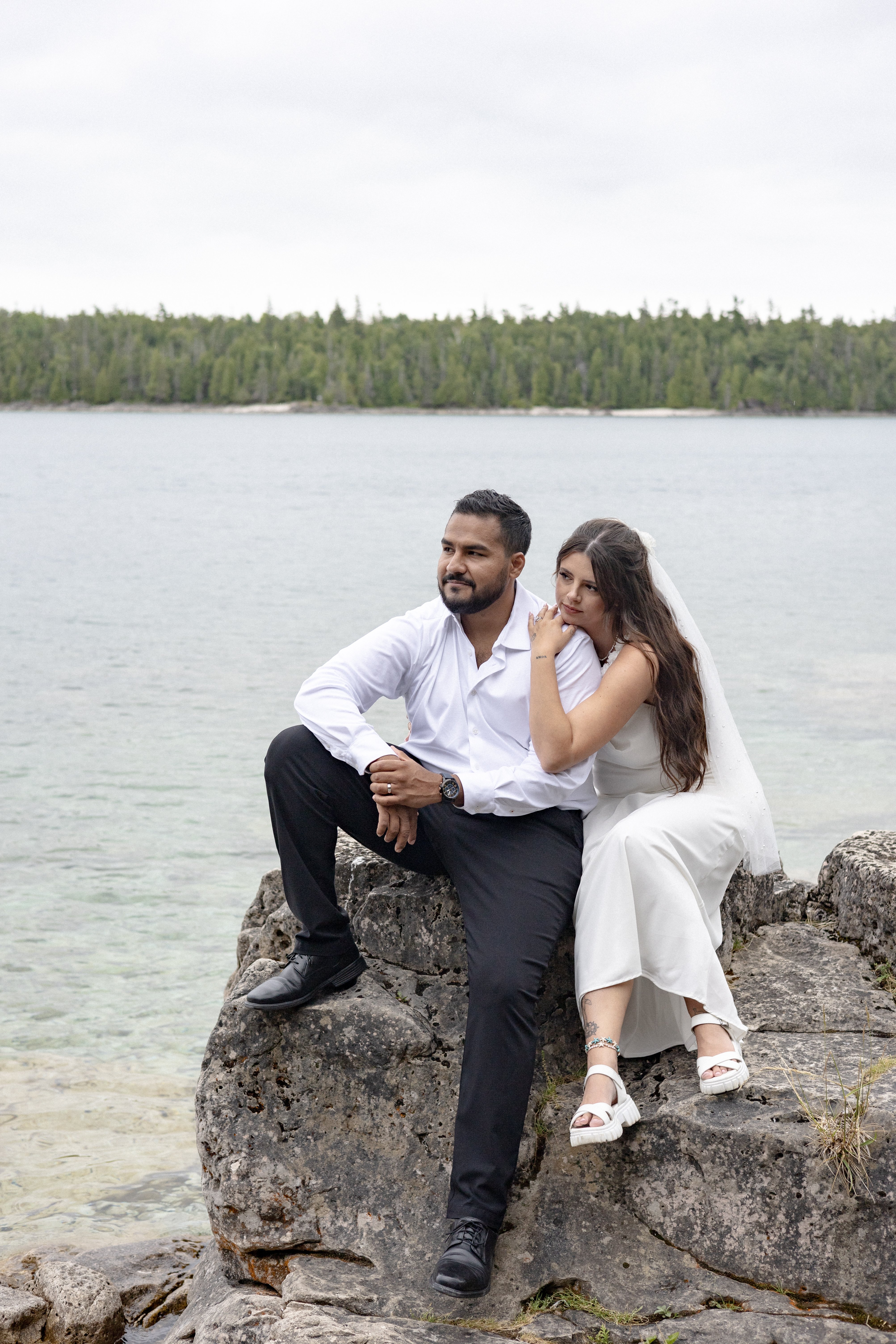 bride and groom sitting on rocks at Tobermory look out