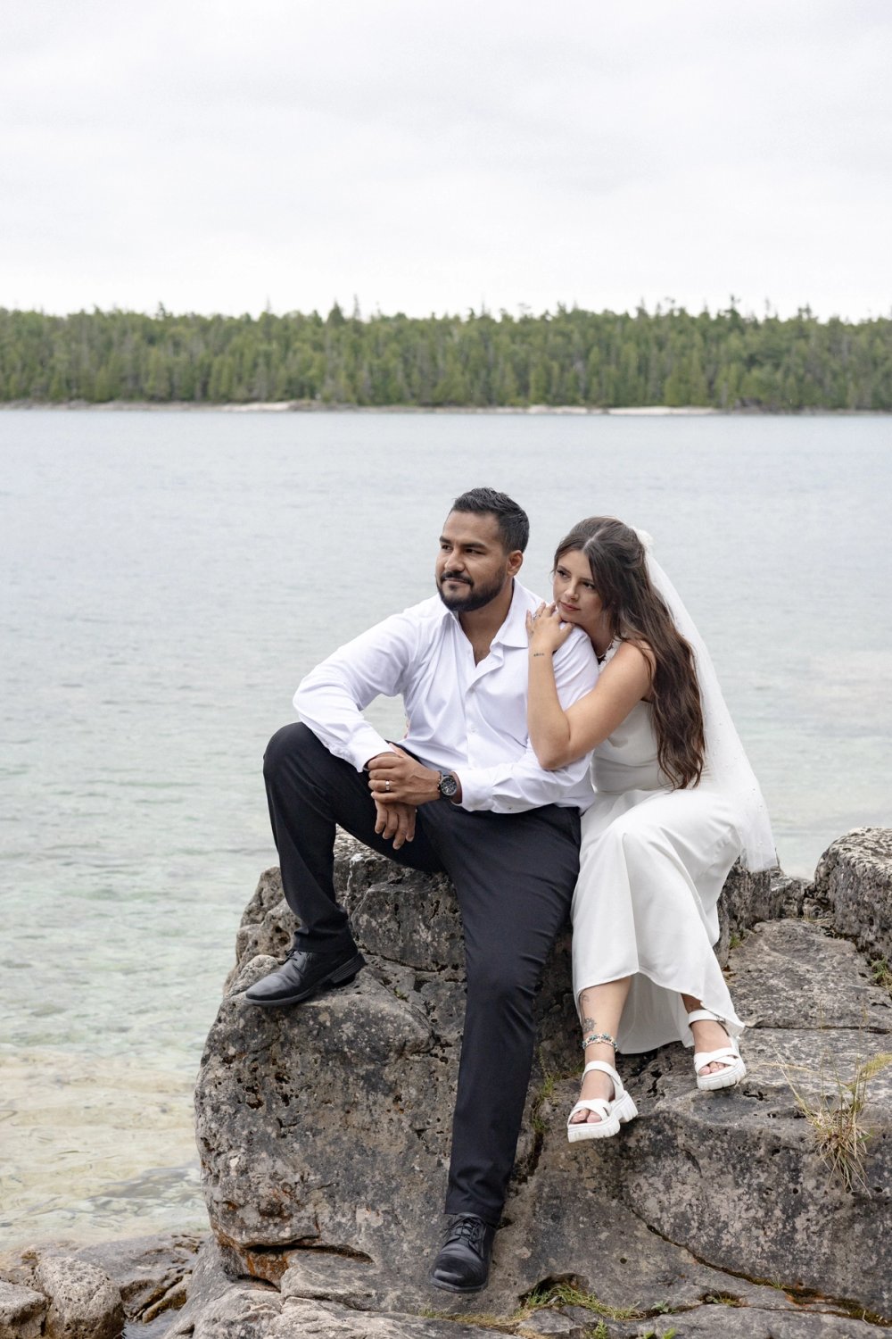 bride and groom sitting on rocks at Tobermory look out
