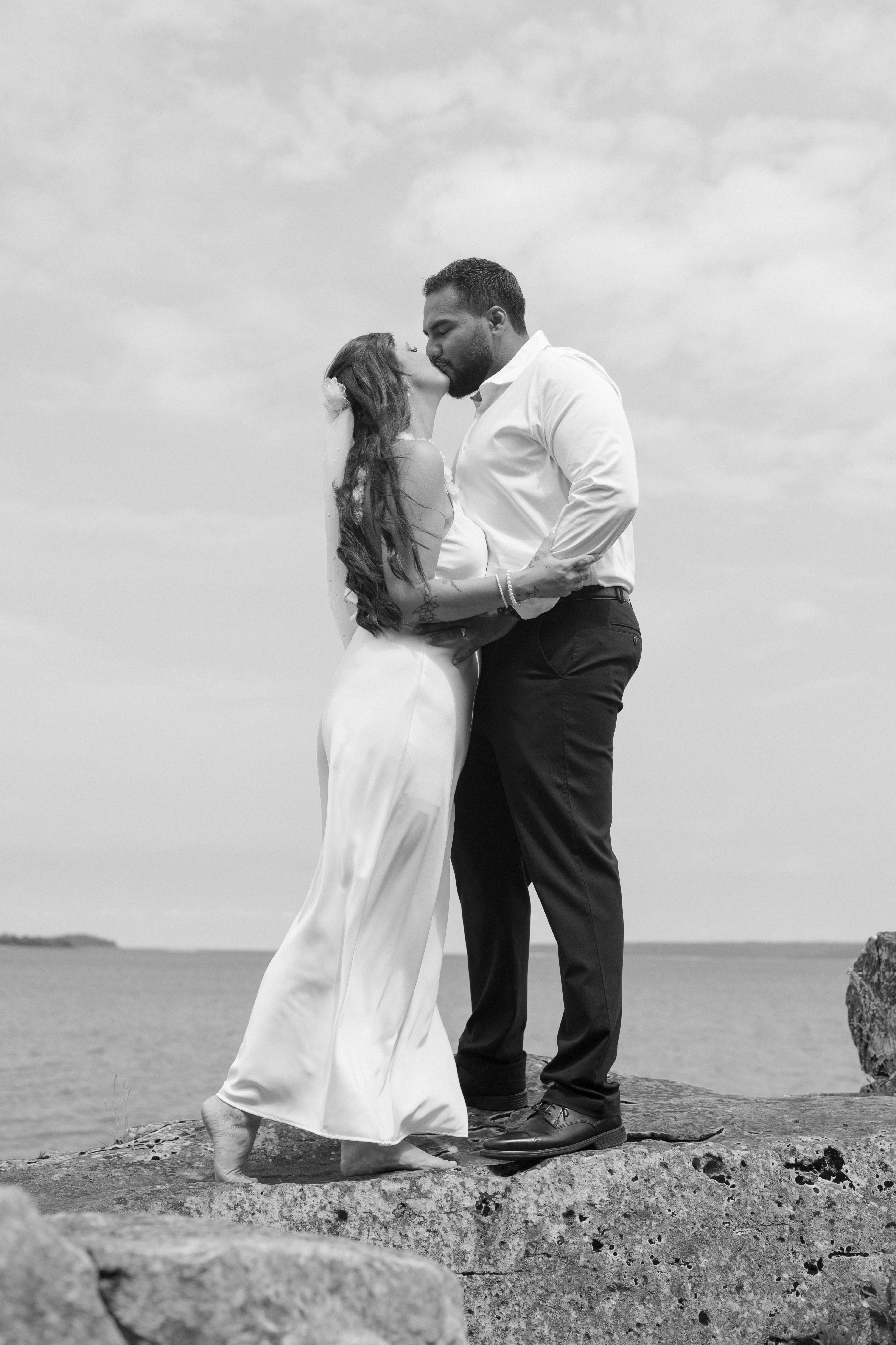bride and groom kissing while standing on rocks - Tobermory Elopement 