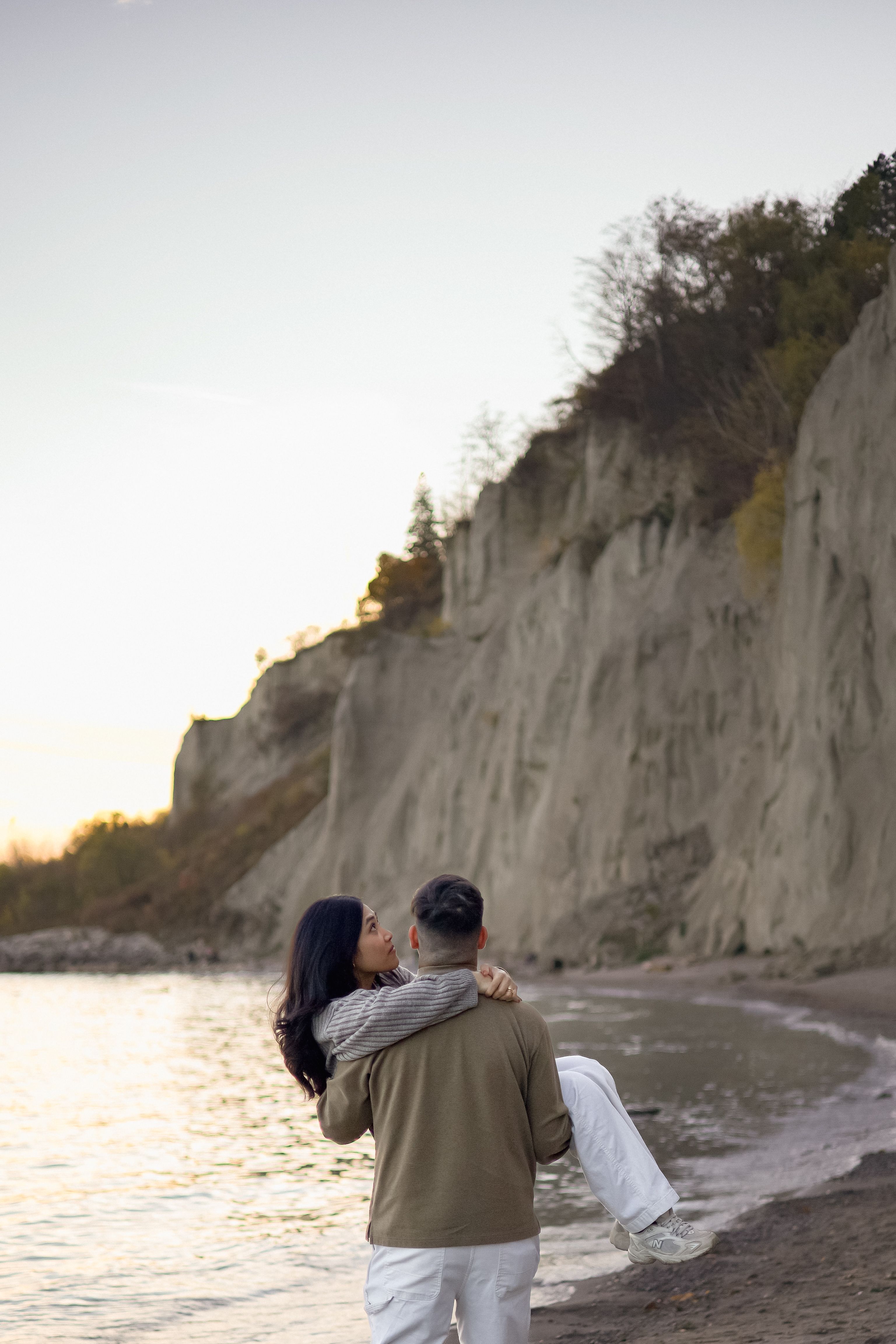 Couple at Scarborough Bluffs Cliff, Husband is carrying wife looking at sunset - Toronto Couples Photography