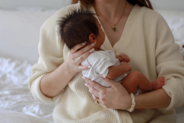 close up image of mother in white knit sweater craddling newborn baby - Newborn Photography