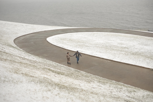 Distance point of view of pregnant woman and her husband walking at a beautiful lakeside path in Scarborough, Ontario.