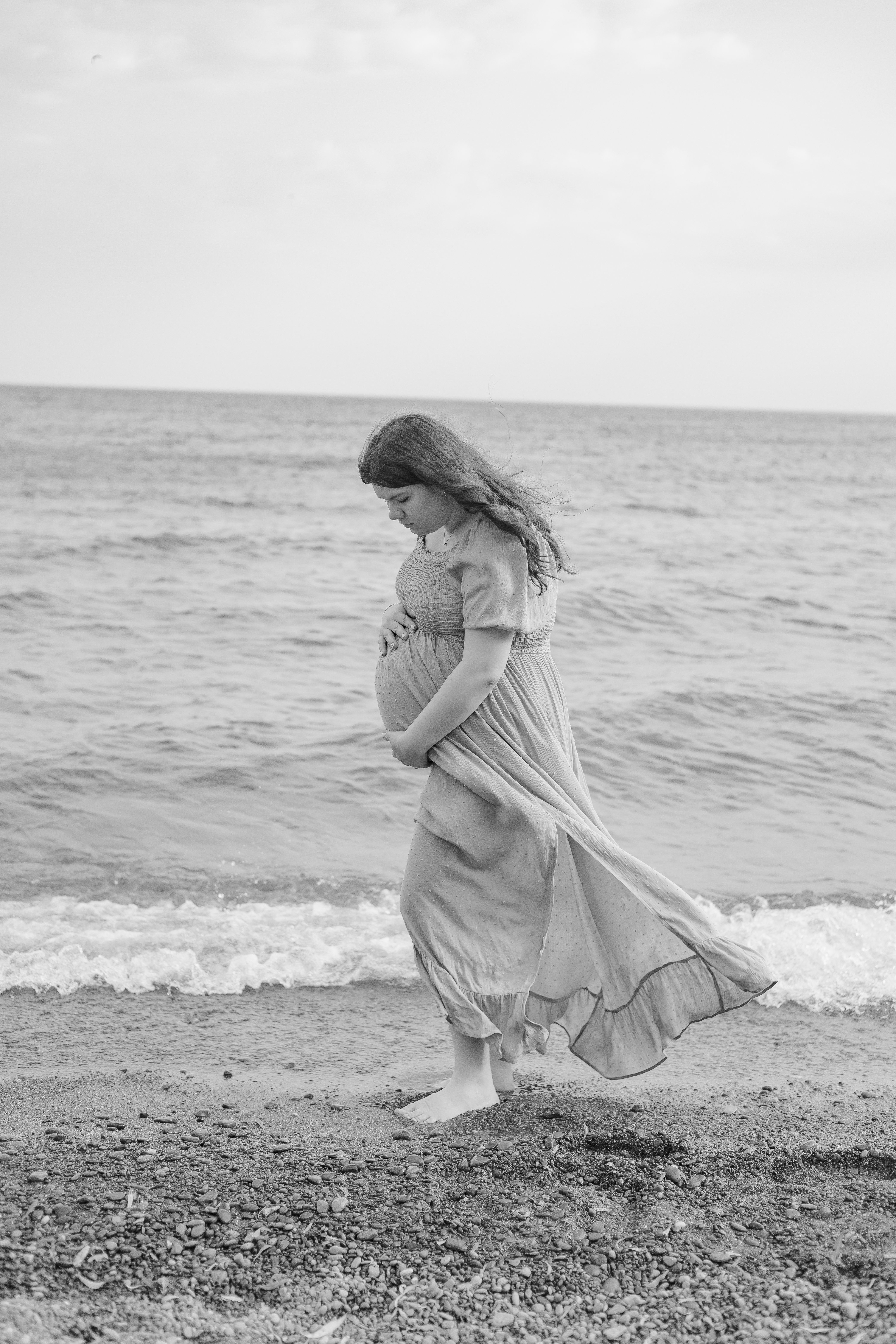 Woman wearing flowing dress at beach for maternity photos, Newmarket, Ontario