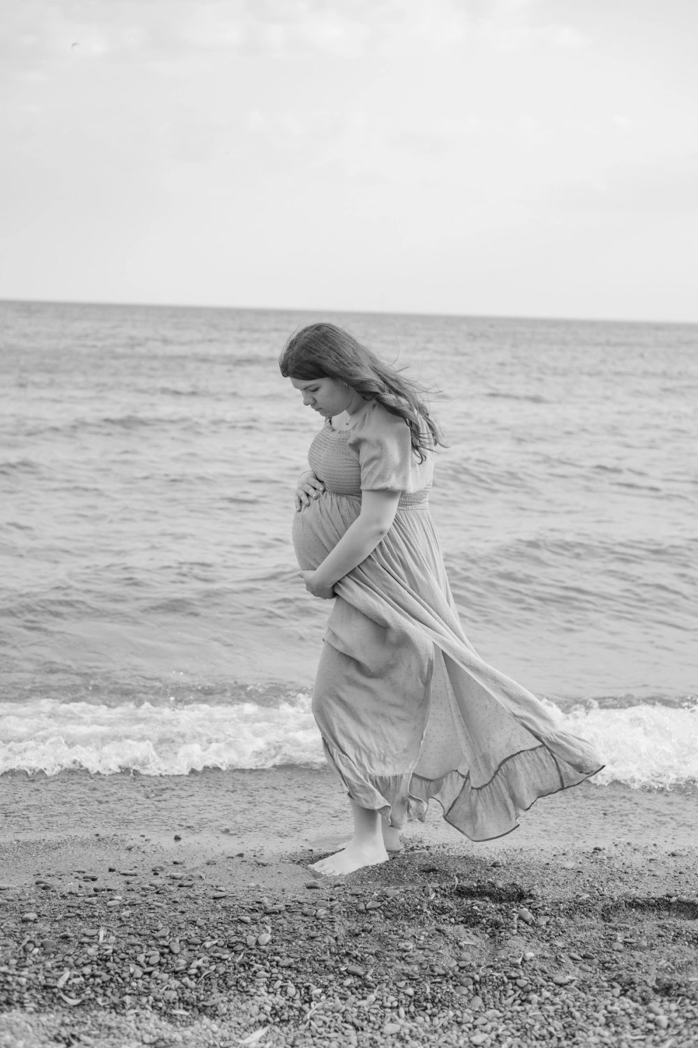 Woman wearing flowing dress at beach for maternity photos, Newmarket, Ontario