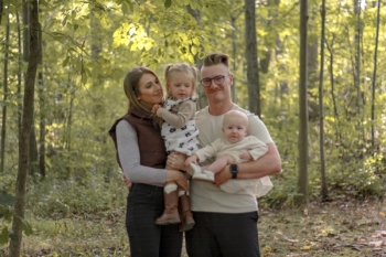 couple with two young daughters posing for family photo in a forest - Family Photography