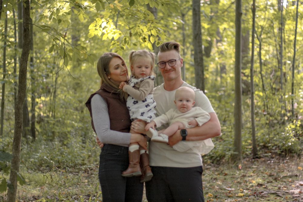 couple with two young daughters posing for family photo in a forest - Newmarket Family Photography