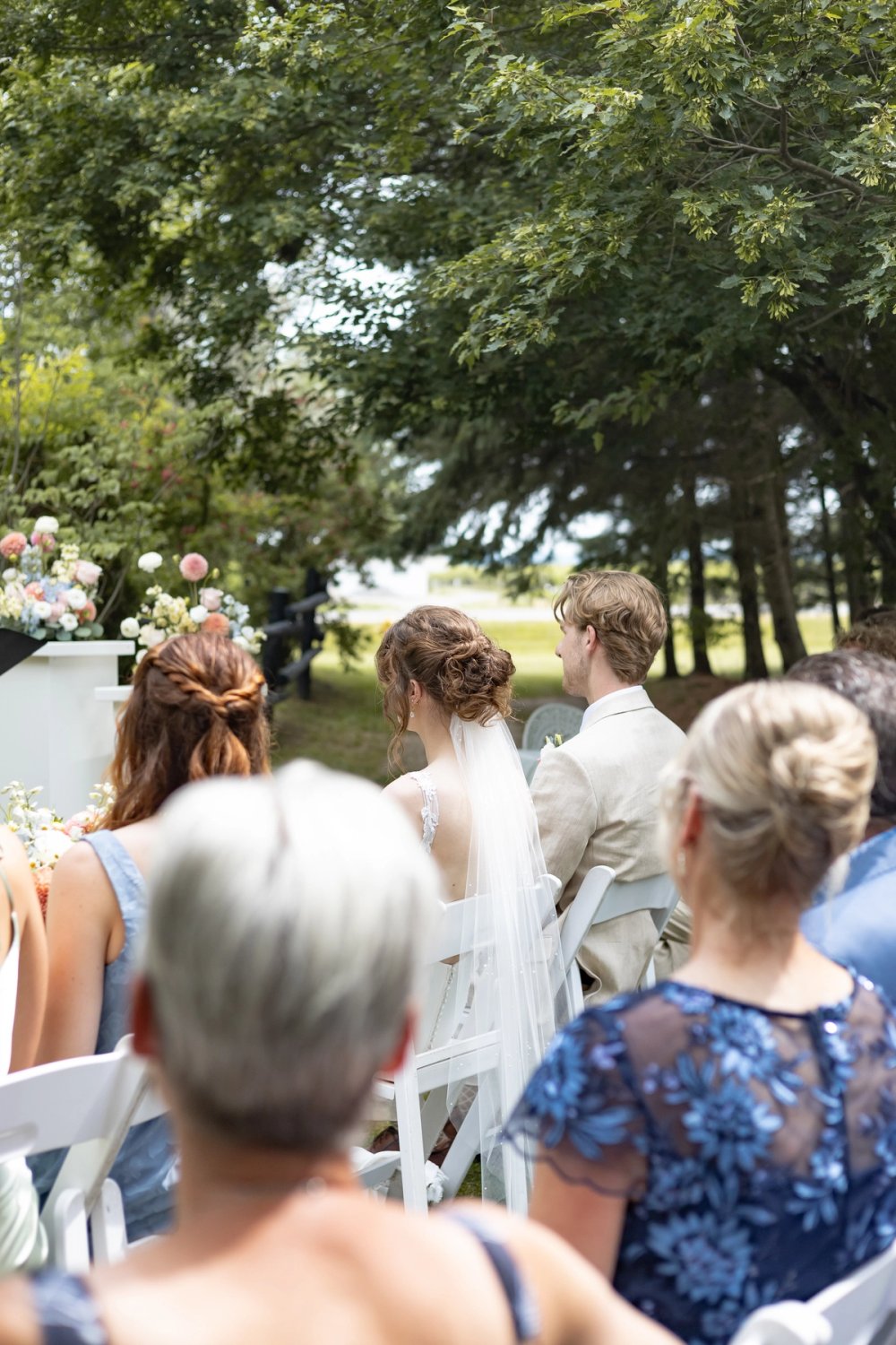 bride and groom seated during wedding ceremony with veil flowing
